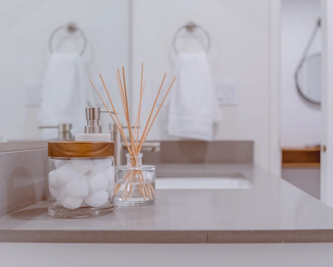 Person using spray bottle and cloth for cleaning a kitchen shelf, ensuring hygiene and cleanliness.